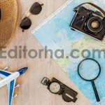 Top view of film camera, straw hat, compass, toy plane, magnifier, sunglasses and world map on