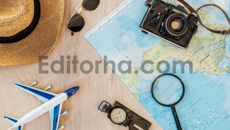 Top view of film camera, straw hat, compass, toy plane, magnifier, sunglasses and world map on