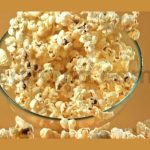 a bowl of popcorn falls on a yellow background fil