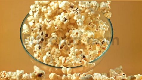 a bowl of popcorn falls on a yellow background fil