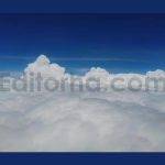 Flying above soft fluffy white cotton clouds against blue sky